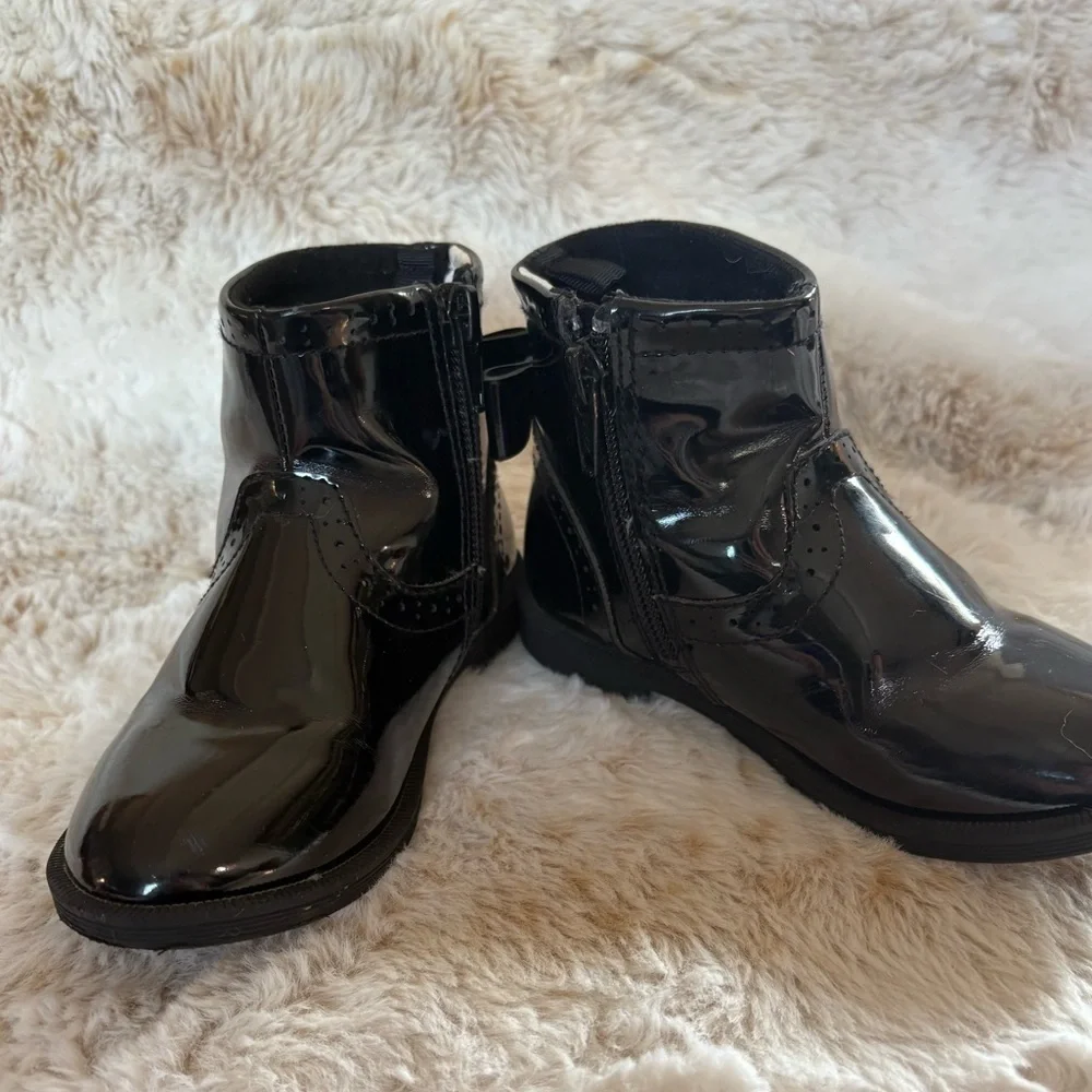 Little girls glossy black boots with bow on the back.